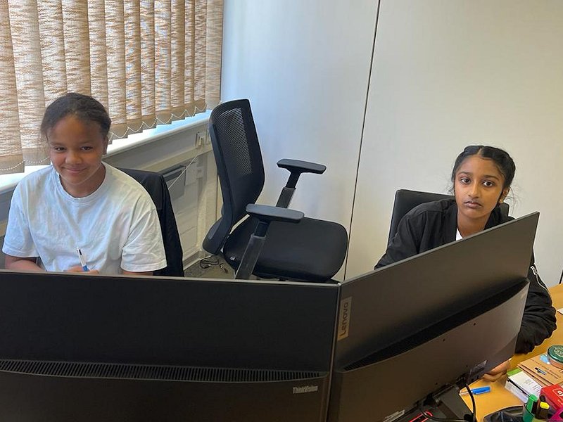 Die beiden Mädchen arbeiten an einem PC mit 2 Monitoren.
