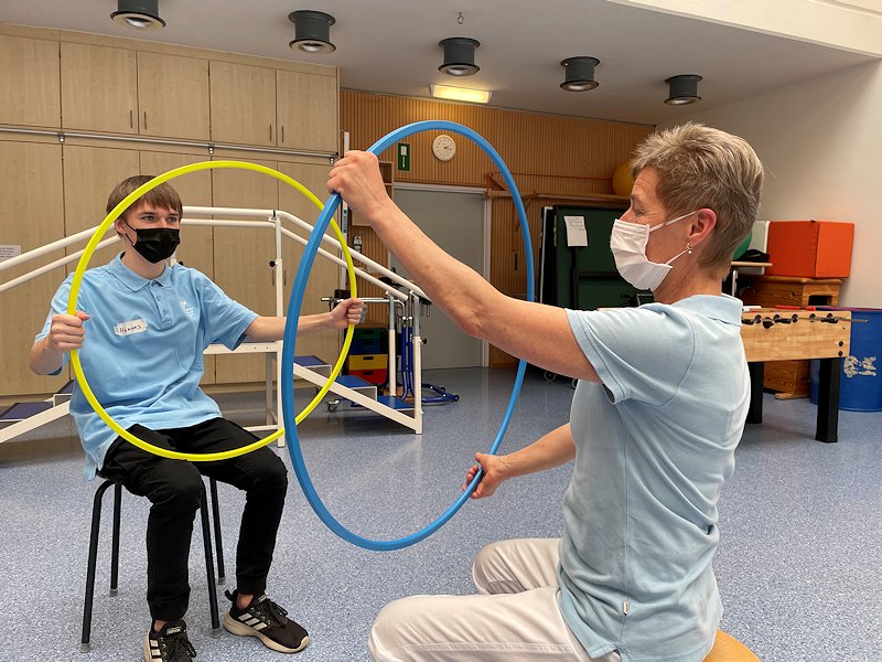 Ein Schüler beteiligt sich mit einem Hula-Hop-Reifen an physiotherapeutischen Übungen