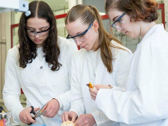 Drei Mädchen arbeiten mit Schutzbrillen im Labor.