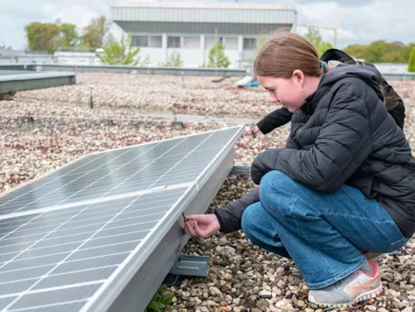 Marie kontrolliert auf dem Dach eine Photovoltaikanlage