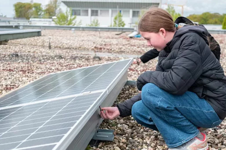 Marie kontrolliert auf dem Dach eine Photovoltaikanlage